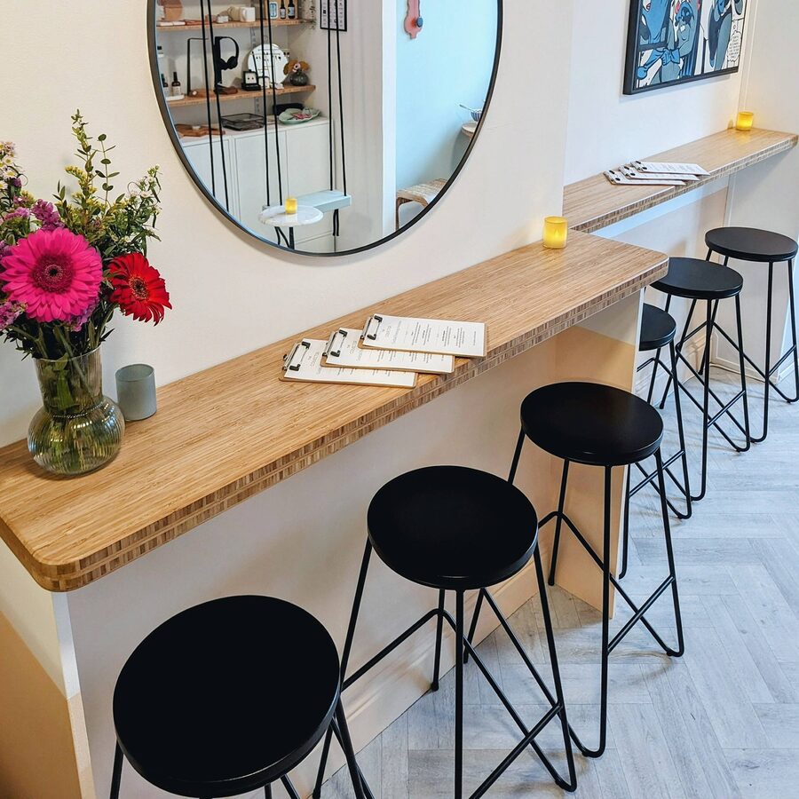 Stools along the bamboo counter beneath a round mirror.