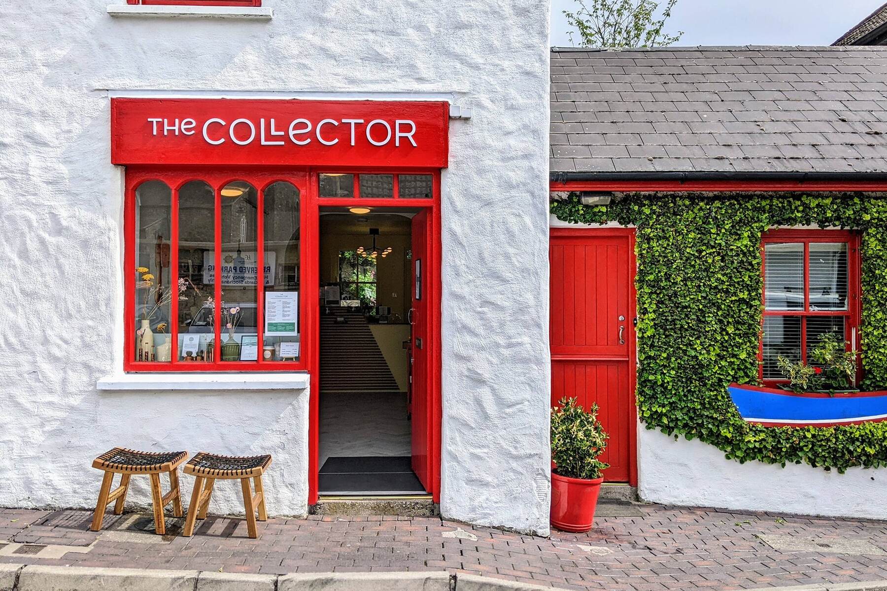 The red-and-white shopfront of The Collector on Market Lane, Kinsale, with the door open and two wooden stools outside.
